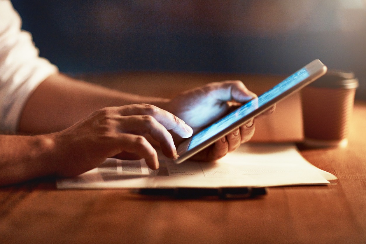 person-hands-using-tablet-in-dim-lighting-at-table