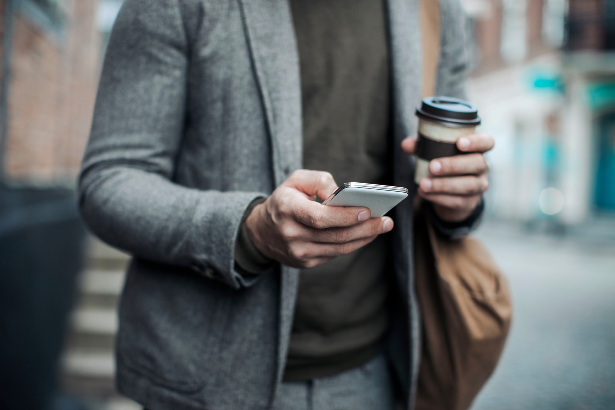 cropped-photo-of-professional-man-holding-coffee-and-using-smartphone-in-city