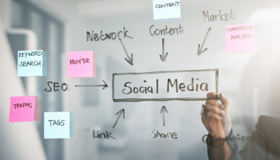person-writing-social-media-concept-map-on-clear-dry-erase-board