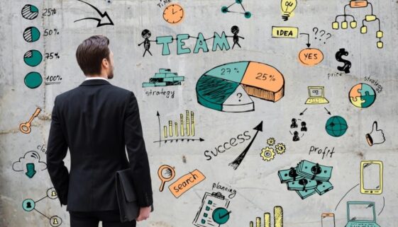 A business man standing in front of an illustration of the different components that go into marketing.