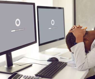 Man lays head on desk while computer website loads slowly.