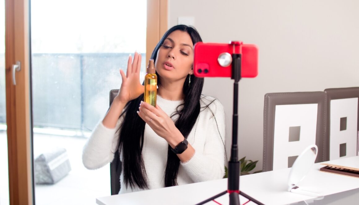 A woman holding up a product in front of her phone camera.
