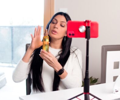 A woman holding up a product in front of her phone camera.