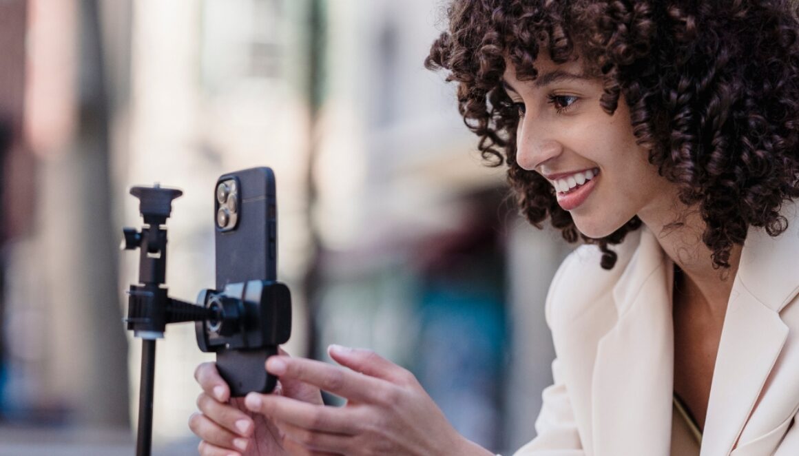 A woman live streaming with her phone on a tripod.