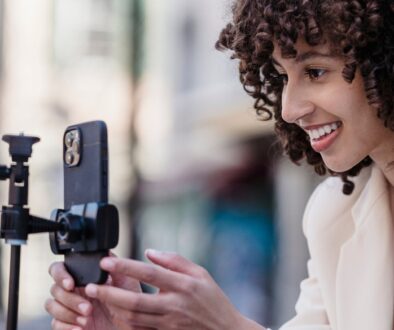 A woman live streaming with her phone on a tripod.