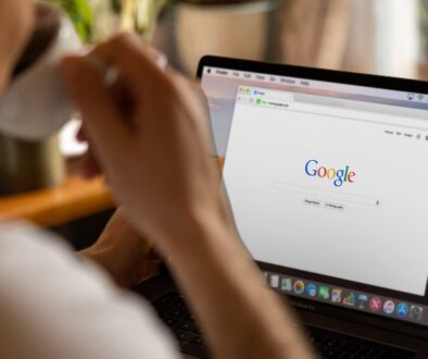 Person sitting at a table with a new Google search tab open on their laptop.