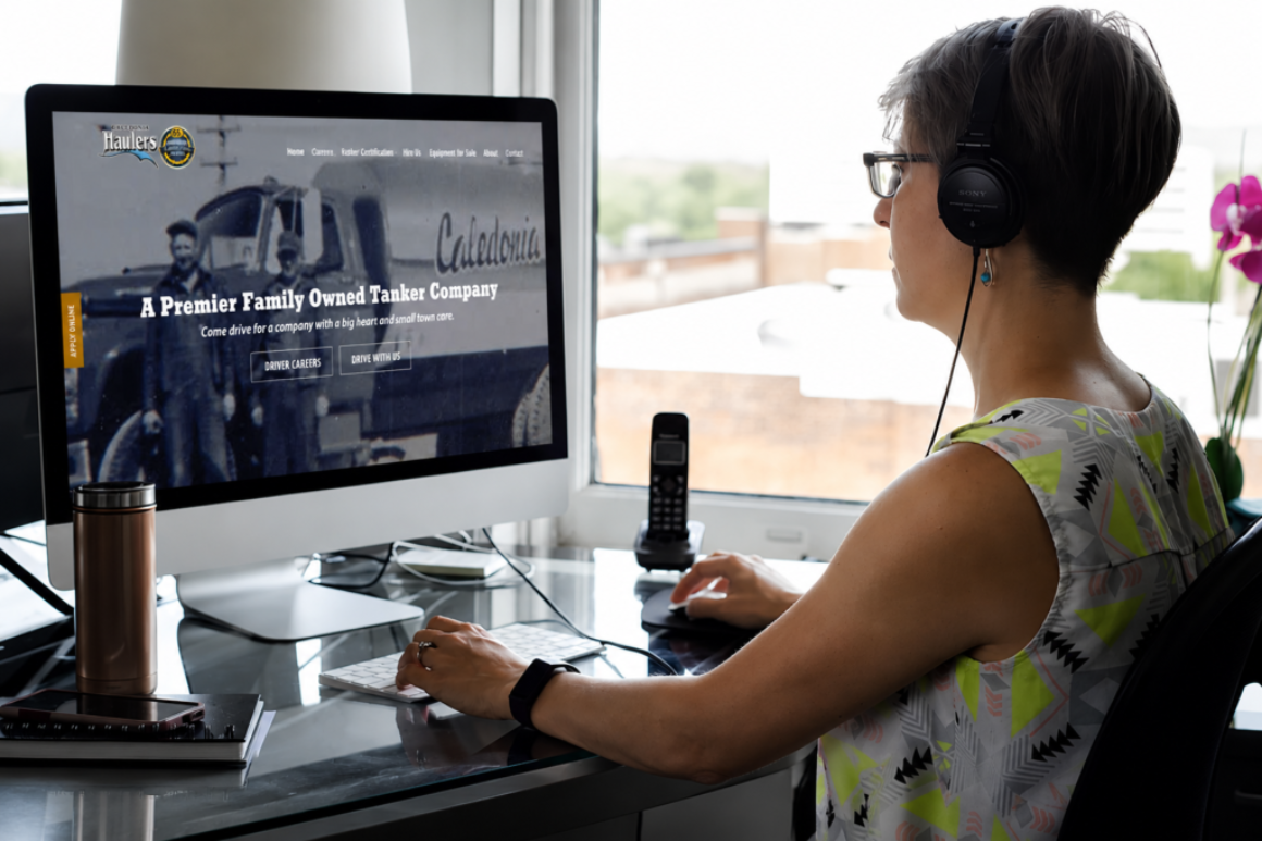 The BLU Group Advertising & Marketing head designer, Lucy, reviews the Caledonia Haulers website on a desktop computer.