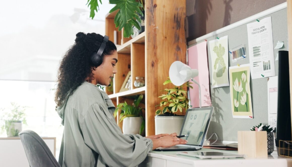 Marketing professional creating content on a laptop with social media analytics and content planning materials nearby.