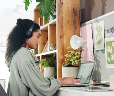 Marketing professional creating content on a laptop with social media analytics and content planning materials nearby.